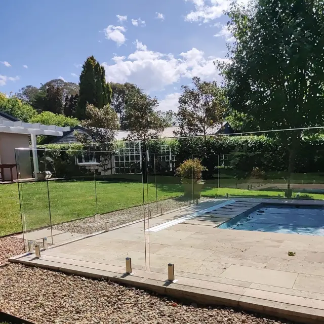 Sparkling glass pool fence beside a garden