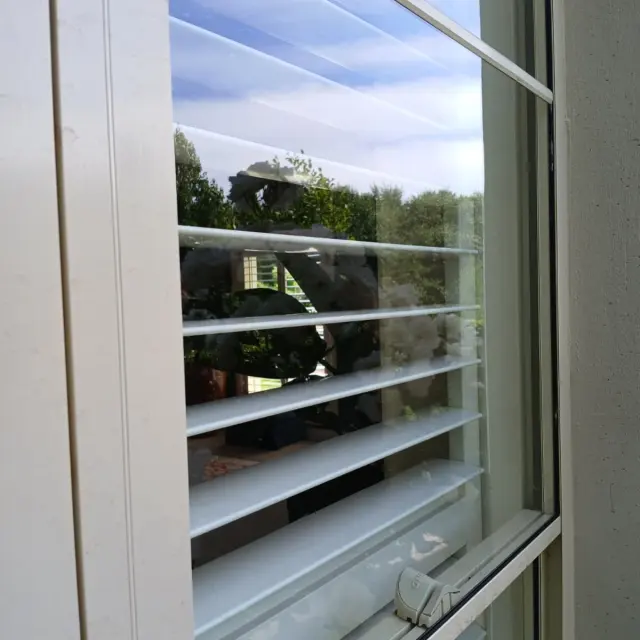 Clean window with plantation shutters behind it