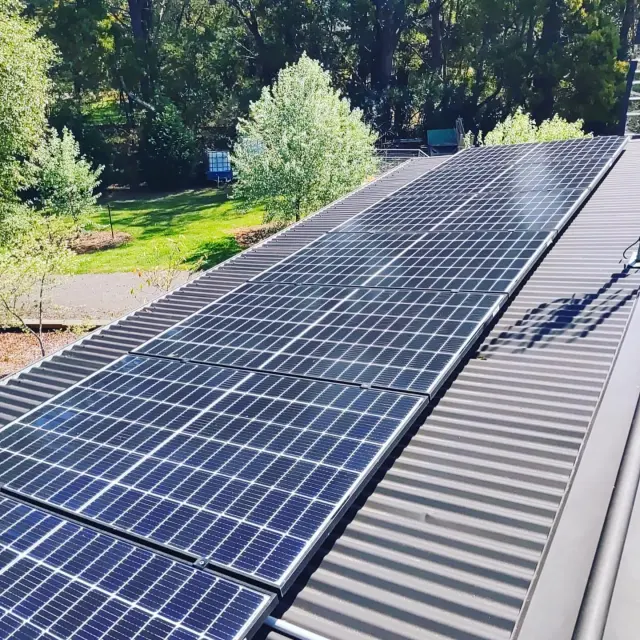 Clean solar panels on a roof beside a garden