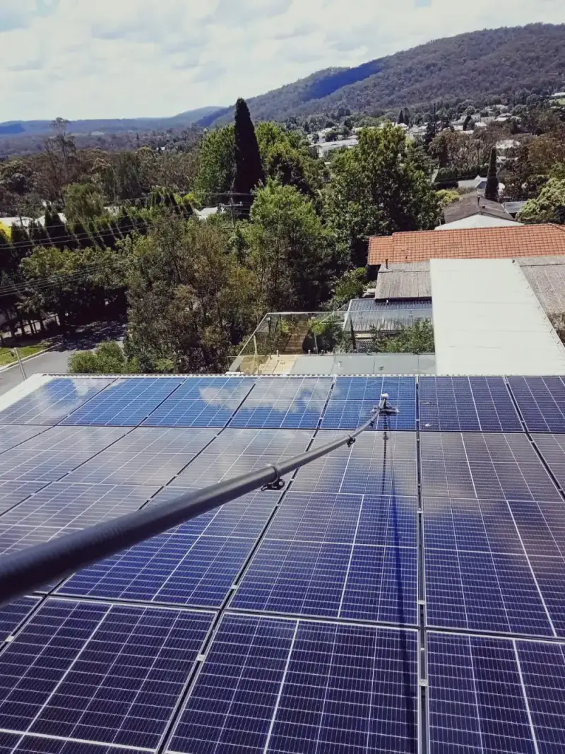 Water-fed pole cleaning solar panels on a roof above the Highlands